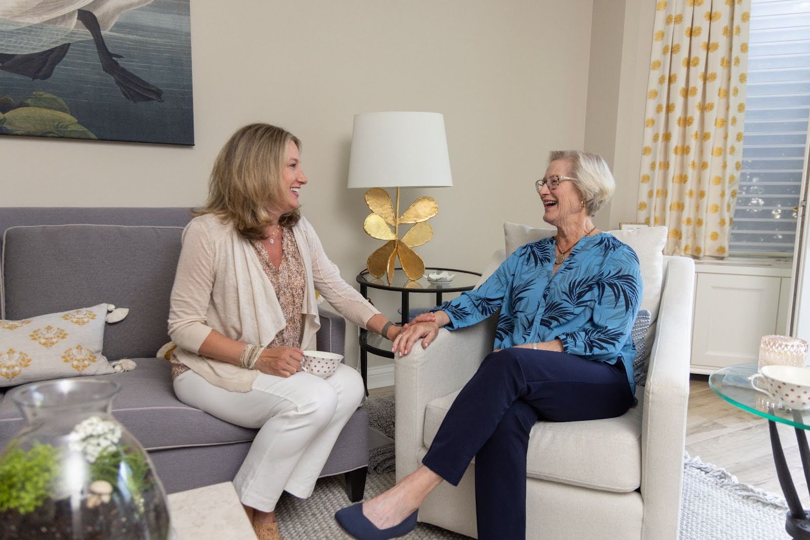 Resident sitting in her apartment home at Lake Forest Place, chatting with her adult daughter.