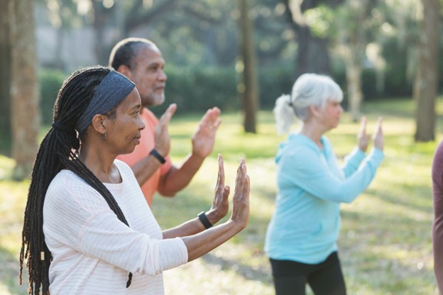 a group of seniors practicing Tai Chi outside on a sunny day