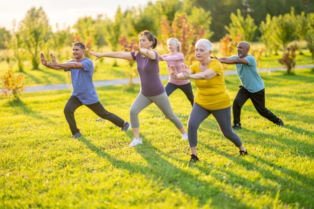 a group of seniors practicing Tai Chi outside on a sunny day