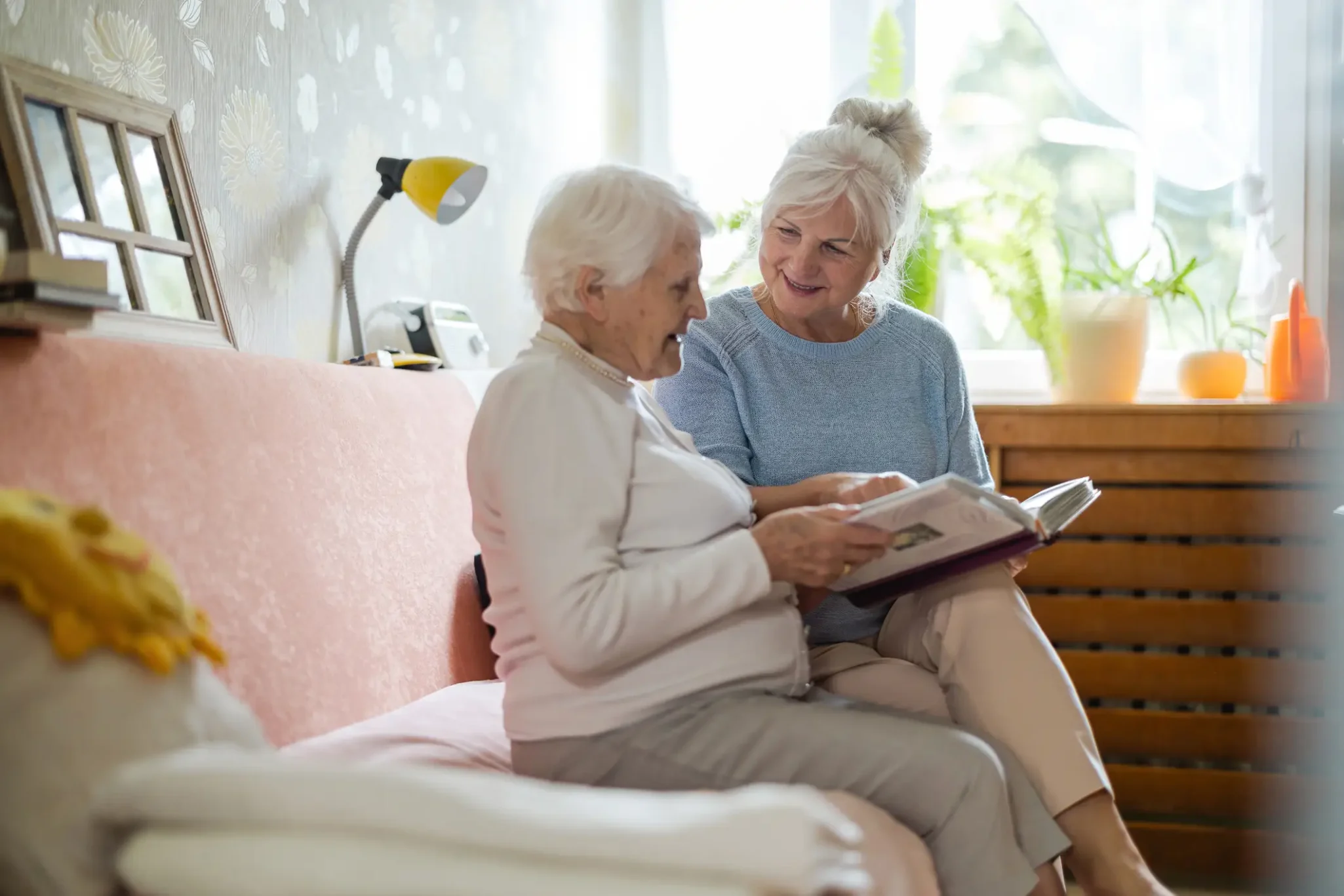 Senior woman reading a book with her adult daughter