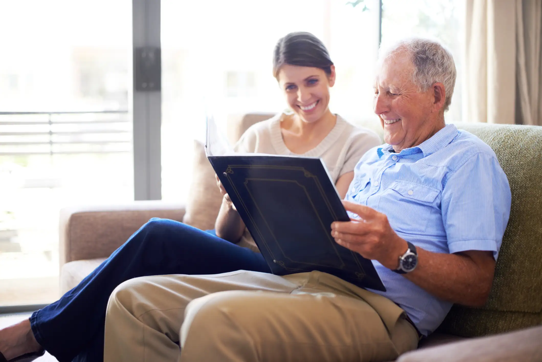 Senior man looking through a photo album with his caregiver