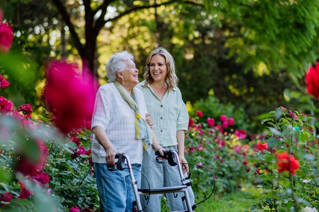 a senior woman and her daughter walking through a peony field