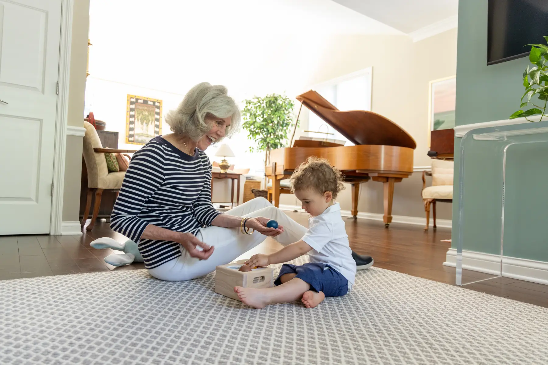 senior woman playing on the floor with her toddler grandson