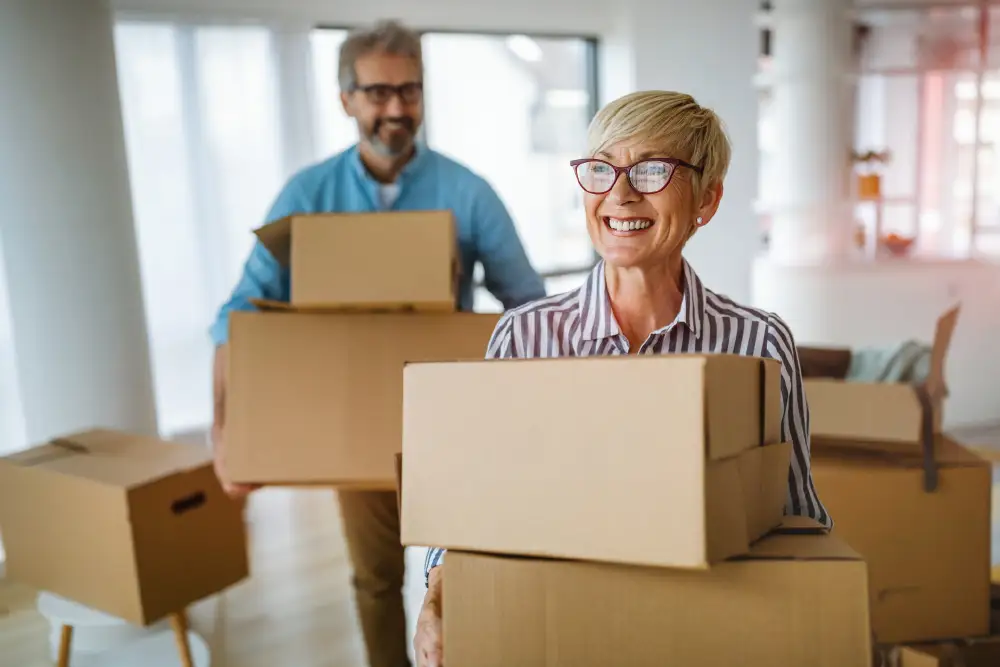 a senior couple carrying moving boxes into their new home