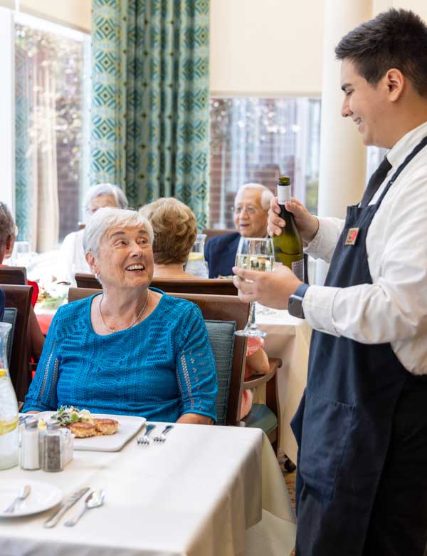 Server pouring wine for a resident who is dining at The Moorings of Arlington Heights