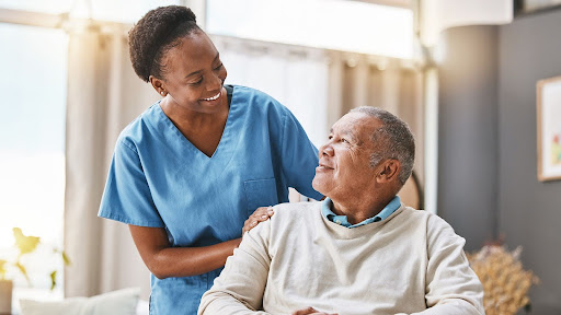 senior man in chair with caregiver smiling