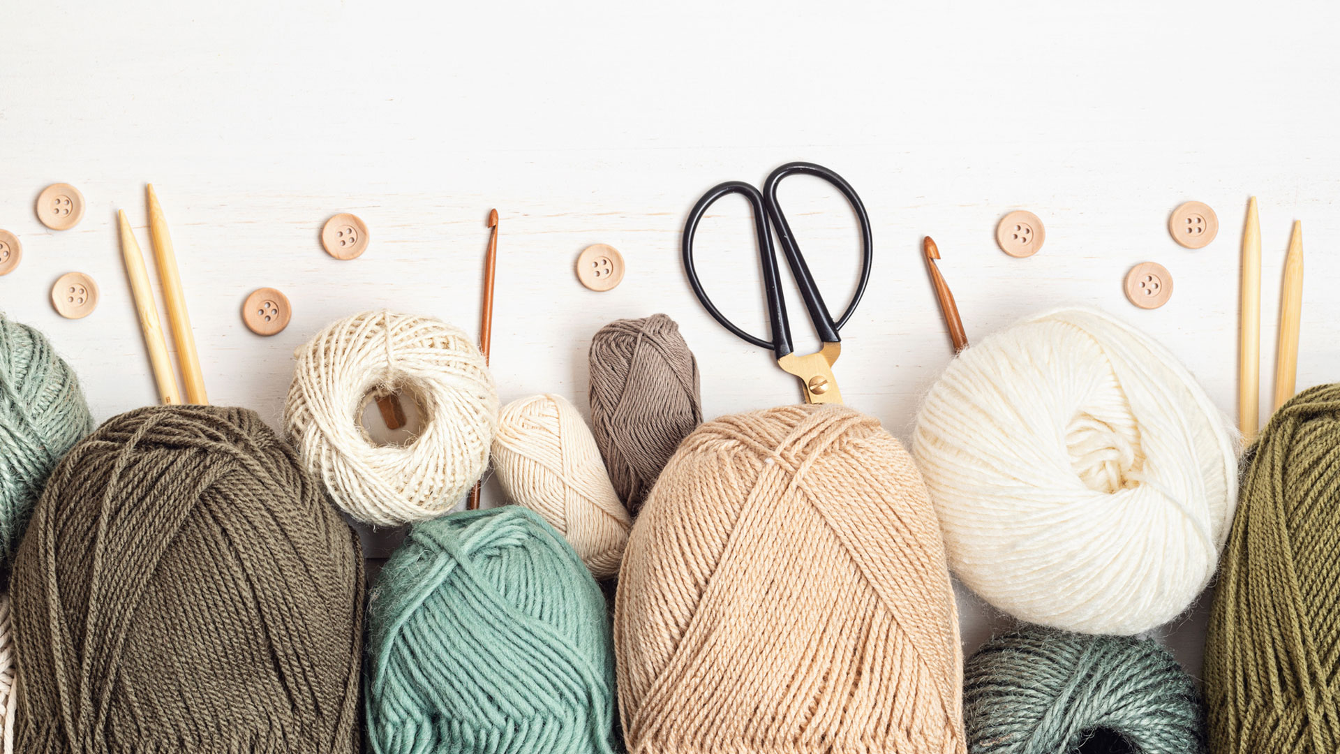 skeins of yarn and knitting needles on a table