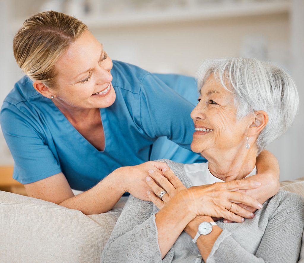 Senior-woman-on a sofa smiling with her caregiver at Westminster Place